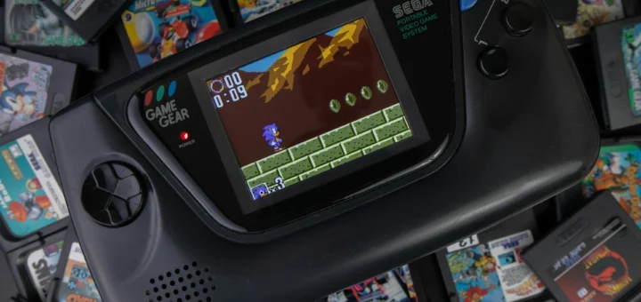 console portable sega game gear affichant un jeu rétro entouré de cartouches