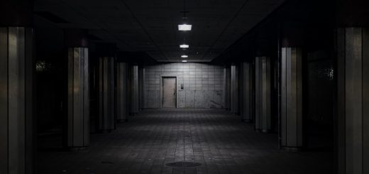Dark, empty underground tunnel with dim lights and a door.