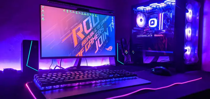 A gaming computer setup with a monitor, keyboard, and tower in purple light