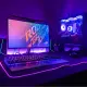 A gaming computer setup with a monitor, keyboard, and tower in purple light