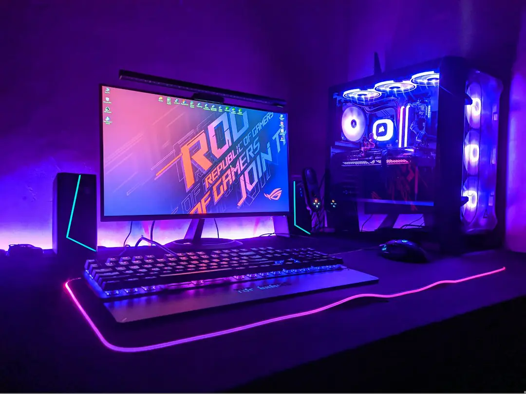 A gaming computer setup with a monitor, keyboard, and tower in purple light