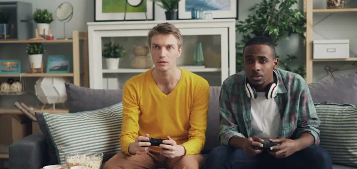 two men sitting on a couch playing video games