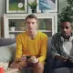 two men sitting on a couch playing video games