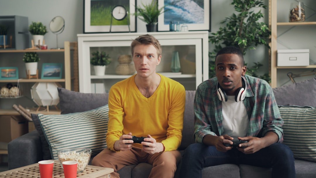 two men sitting on a couch playing video games
