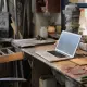 From above of modern laptop laying at table among different tools and equipment in workshop