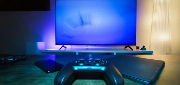 A stylish and ambient gaming setup featuring a controller, smart devices, and a TV in a lit living room.